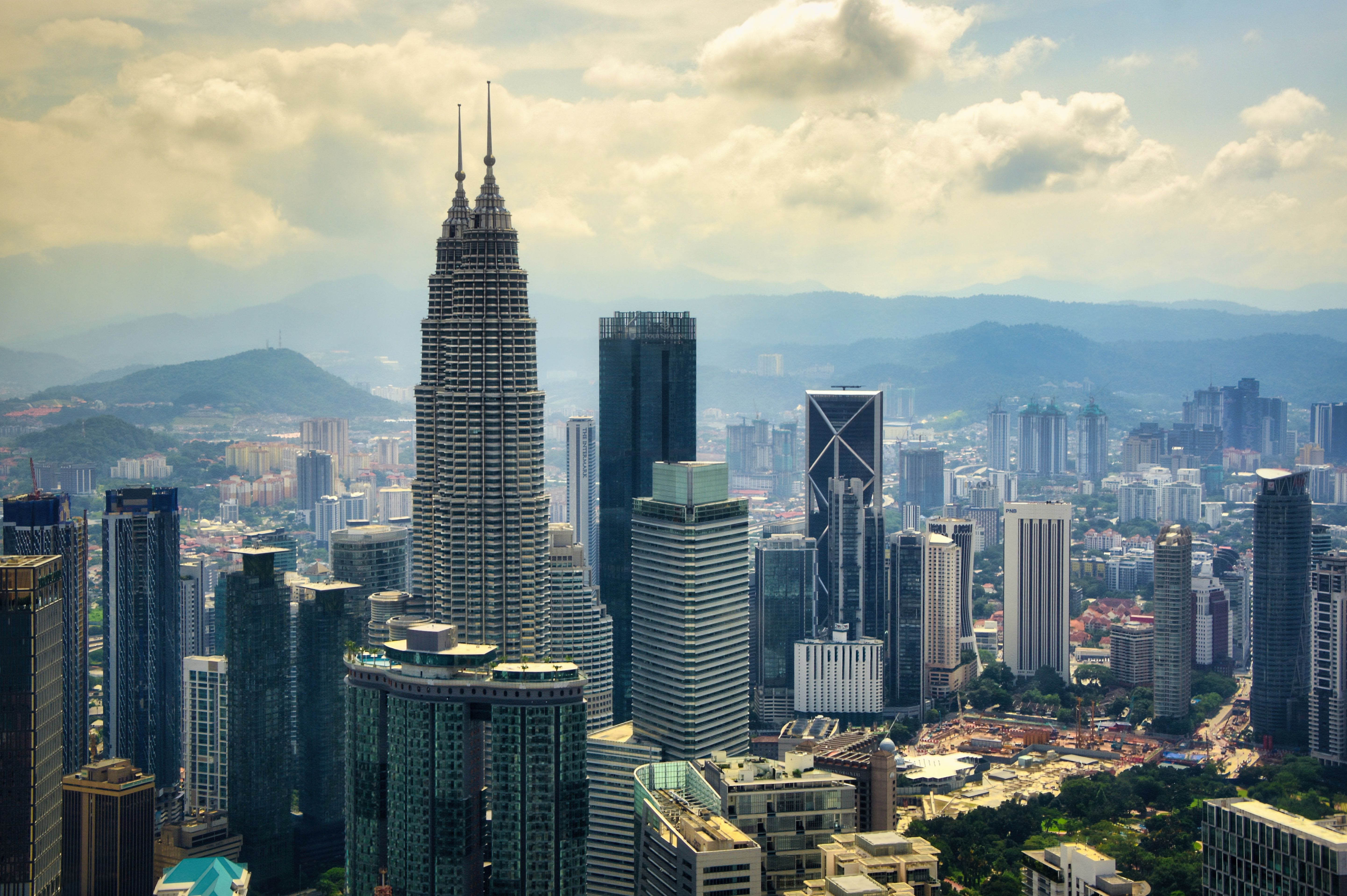 Petronas Twin Towers and Kuala Lumpur city skyline beneath sunlit clouds, Malaysia