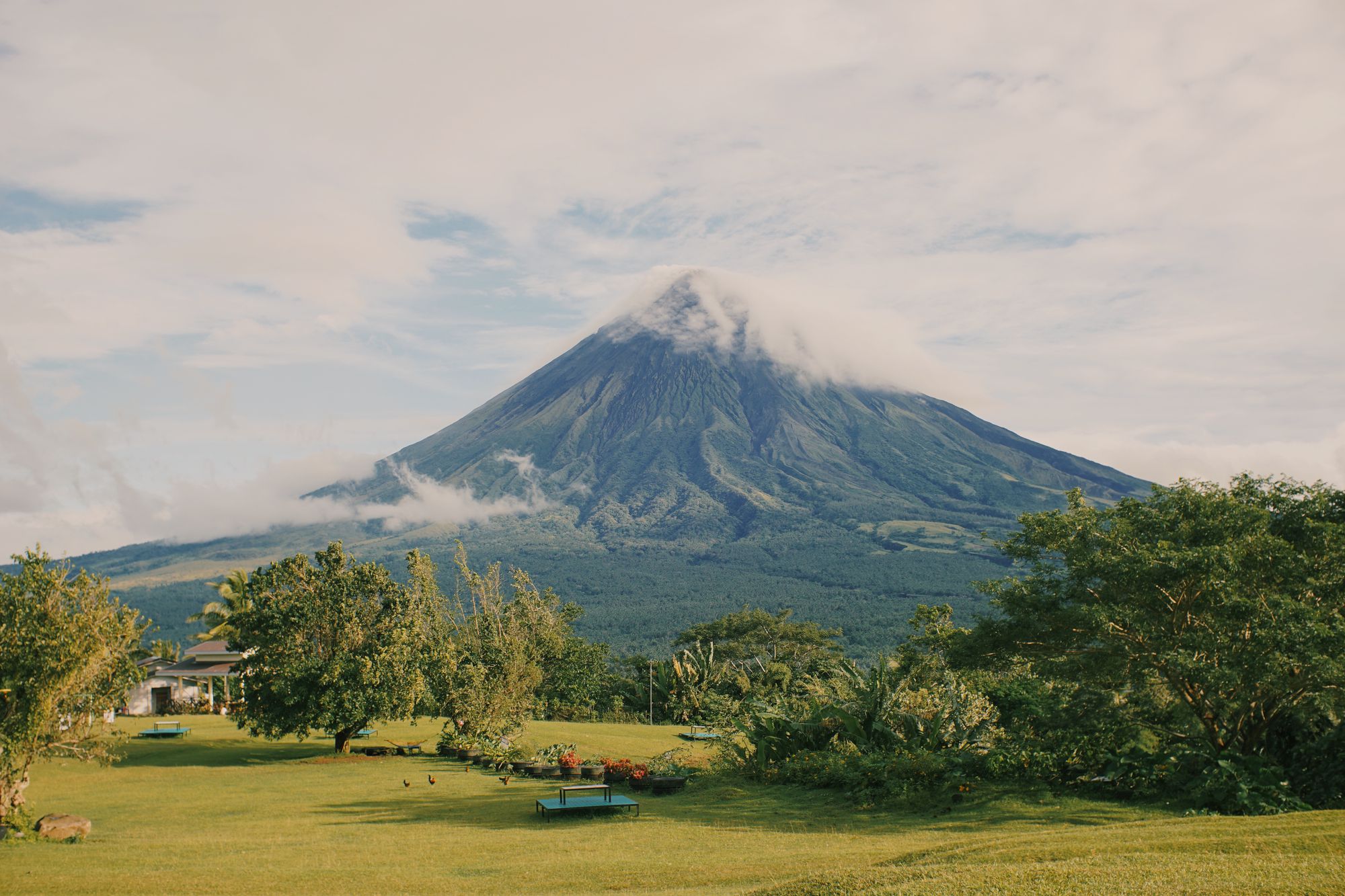 Mayon Volcano with a cloud-covered summit and lush green surroundings in the Philippines