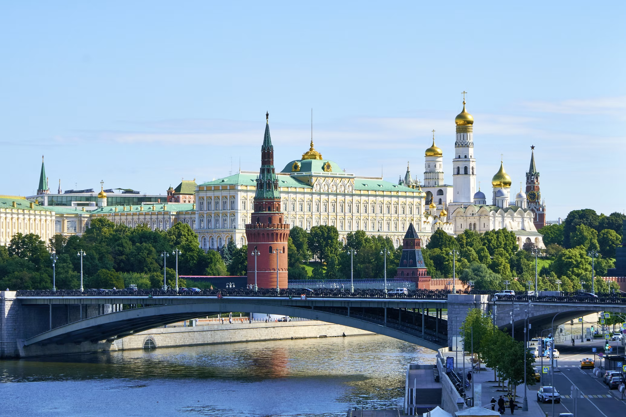 The Moscow Kremlin beside a river and bridge under a clear blue sky, Russia