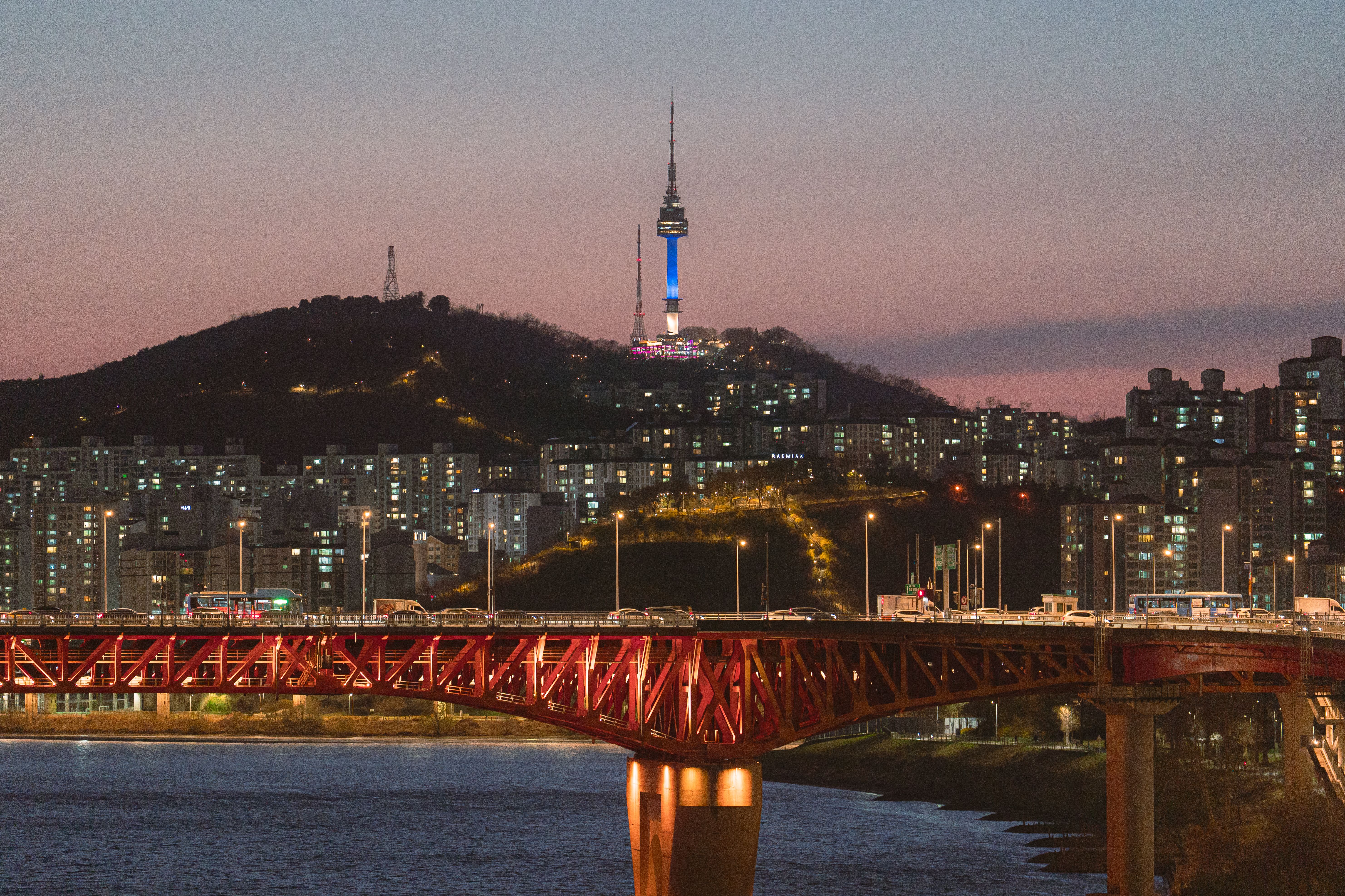 Illuminated tower above the Seoul skyline and a red bridge at dusk, South Korea